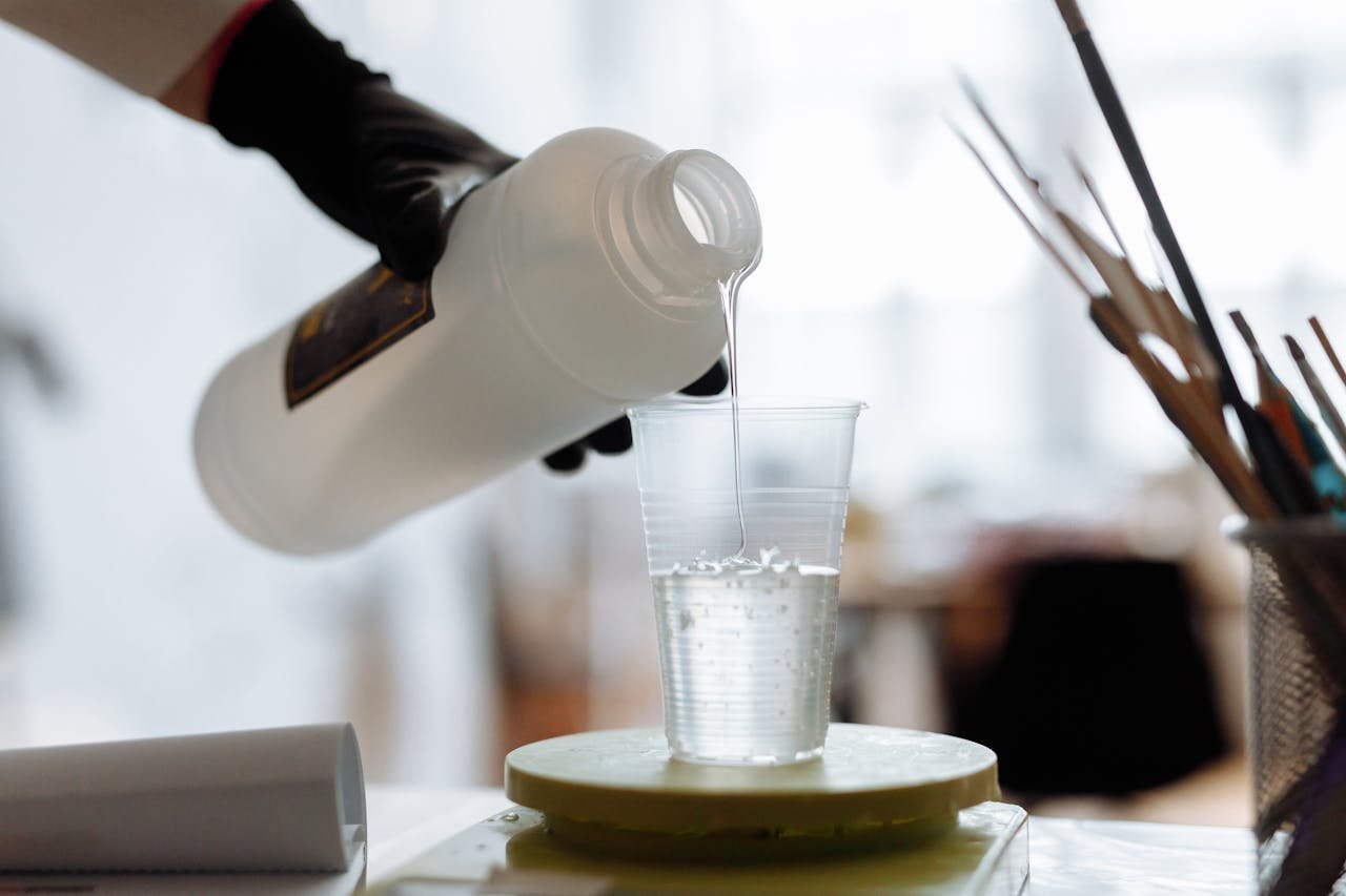 Close-up of liquid resin being poured into a plastic cup indoors.